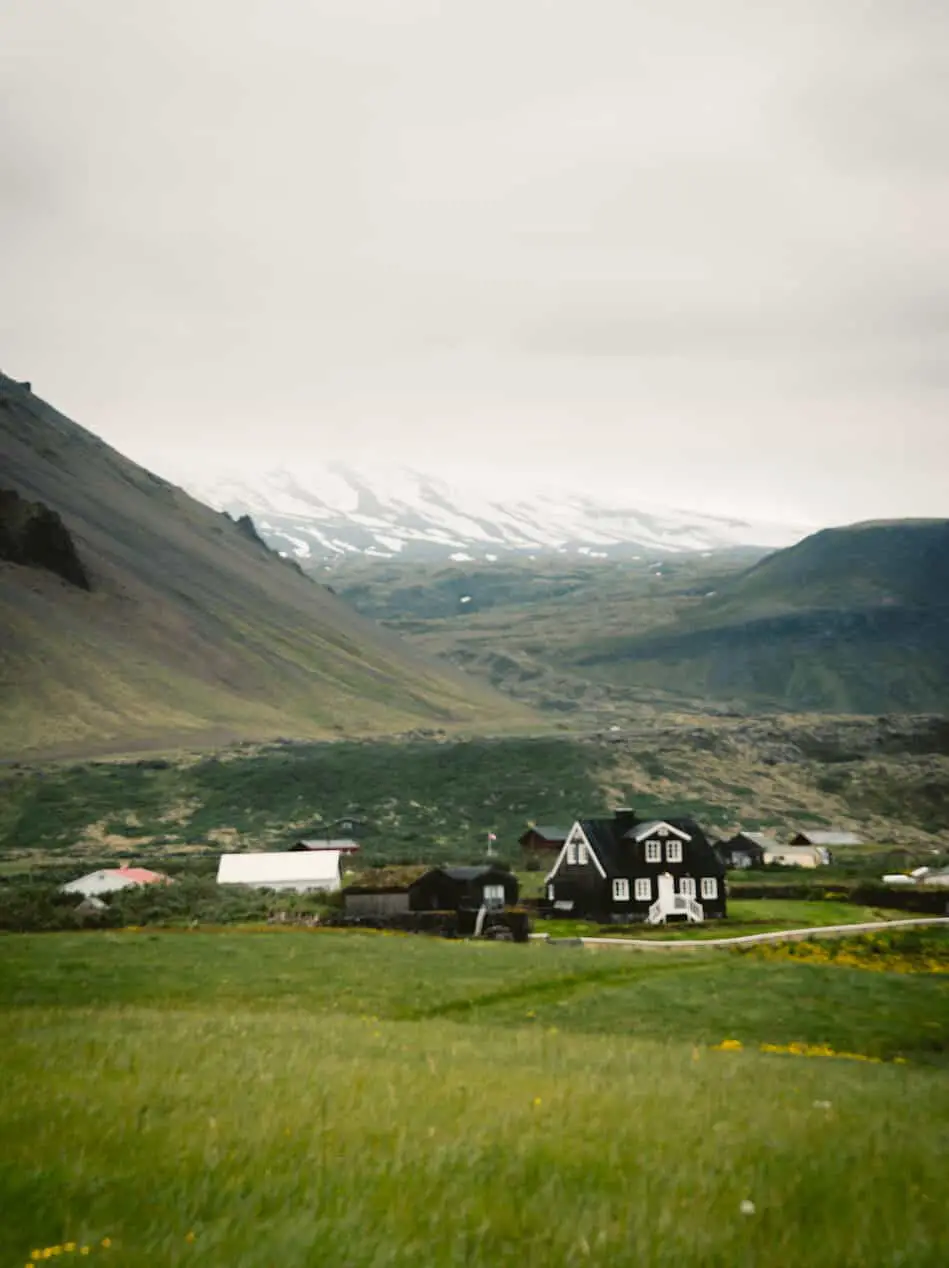 brown and white house in front of mountains in Iceland